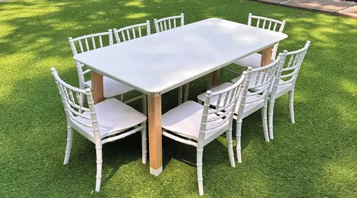 Mesa rectangular blanca con ocho sillas en jardín