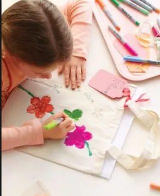 Niña decorando una bolsa de manta con flores